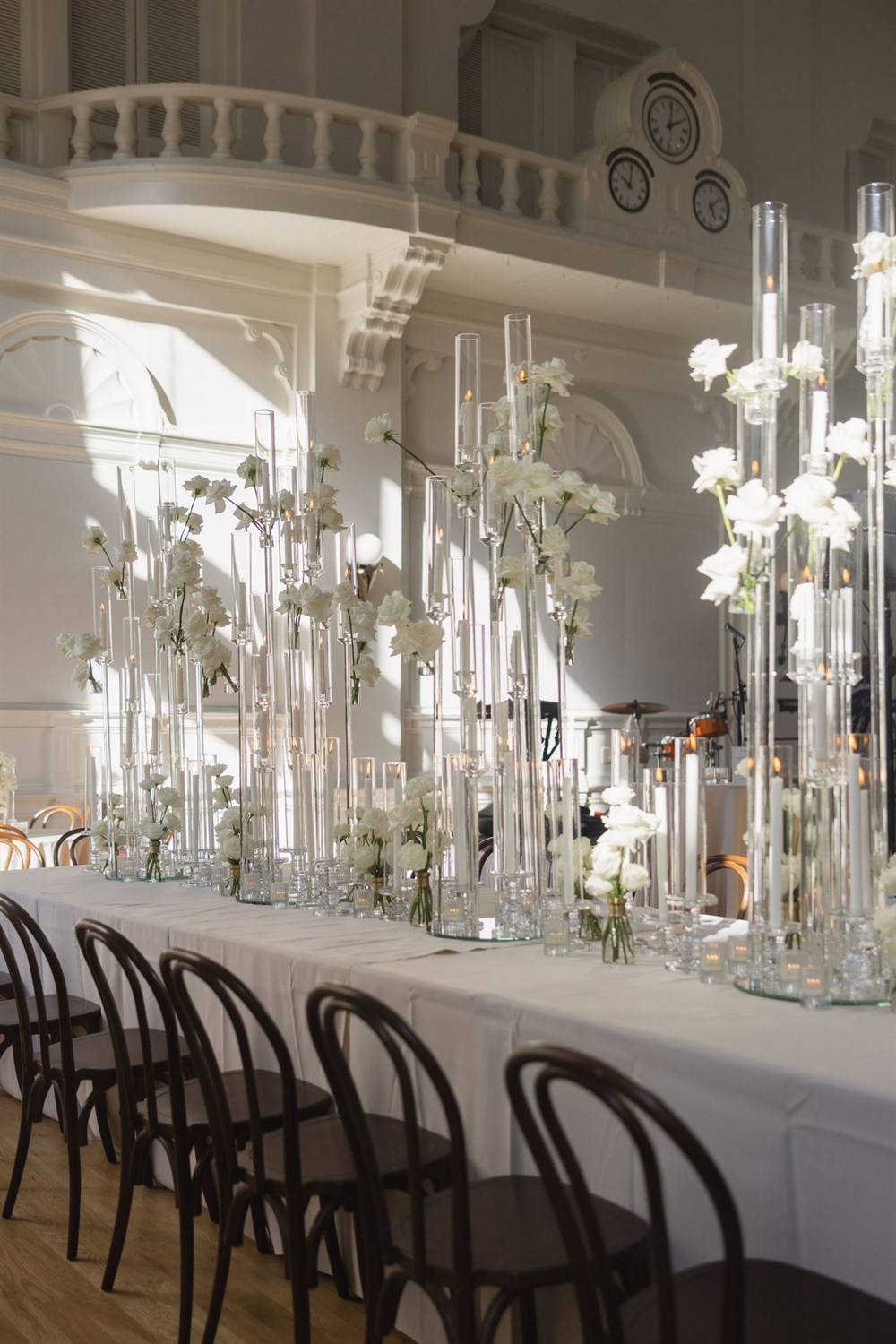 A ceremony aisle lined with tall glass stands of white florals