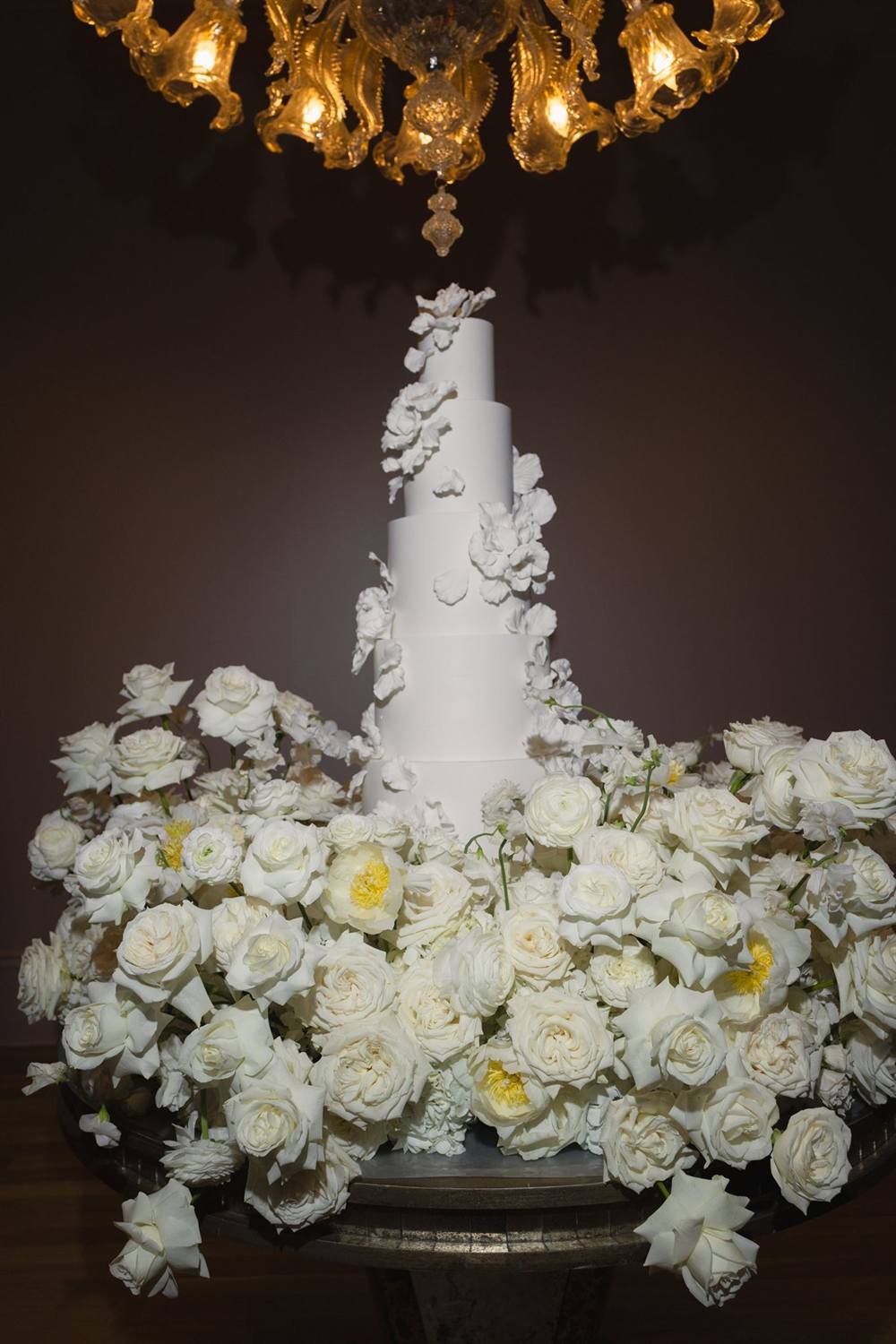 A white wedding cake trimmed in orchids and garden roses
