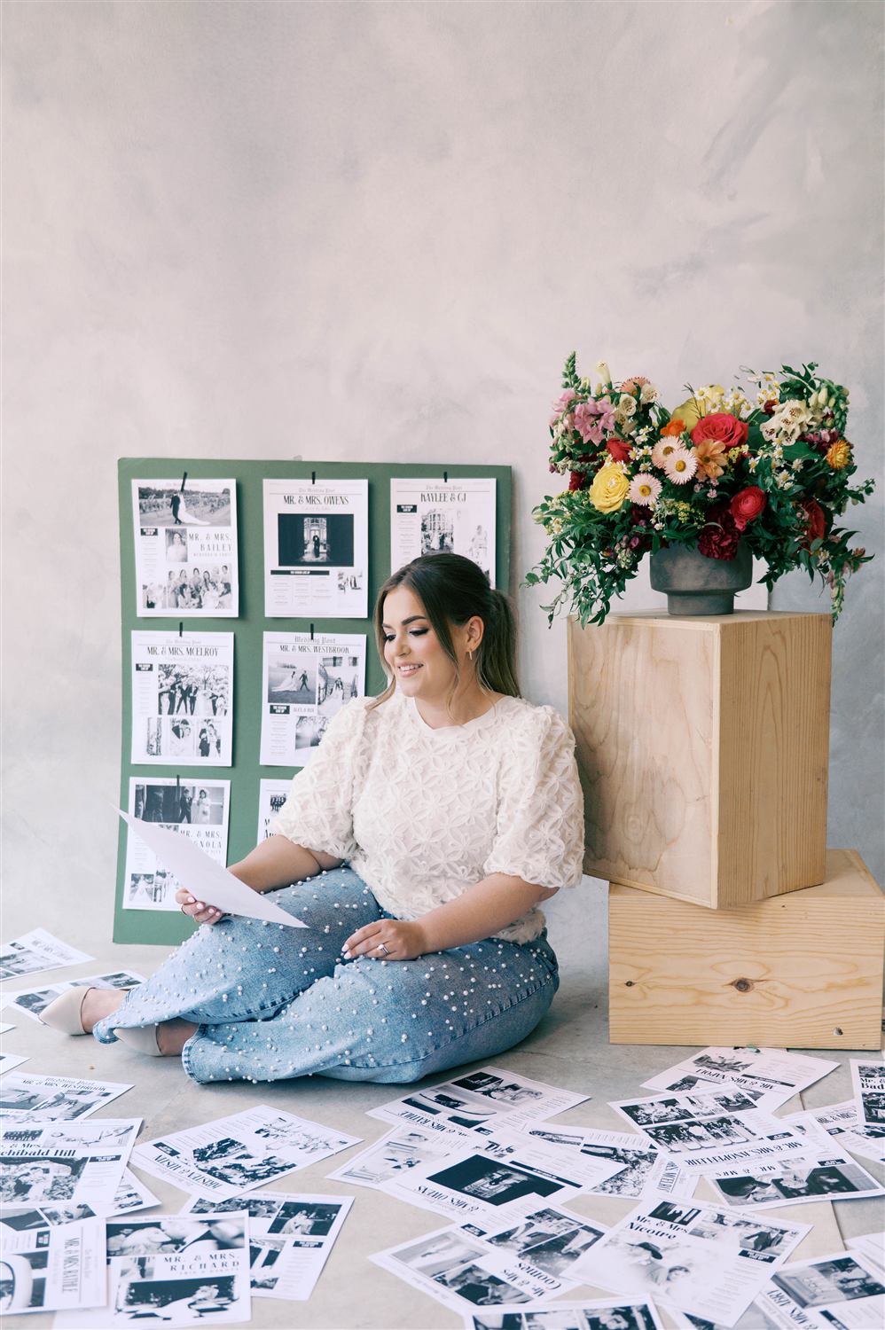 Nancy sits beside a wedding mood board and a fresh arrangement