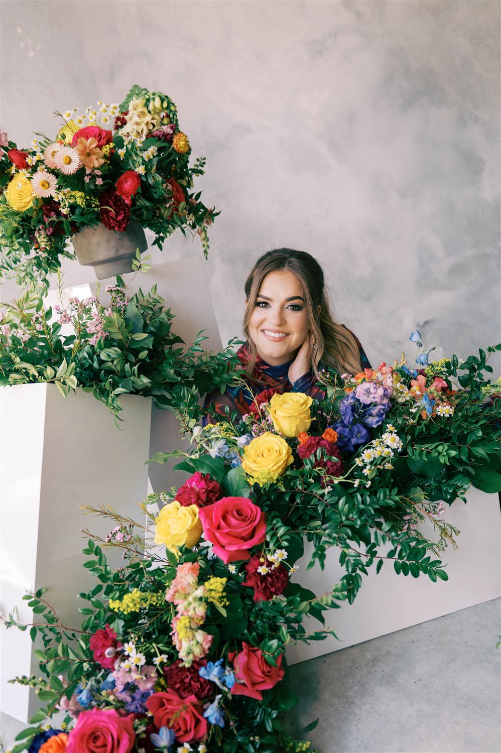Nancy smiles from within a floral installation she built