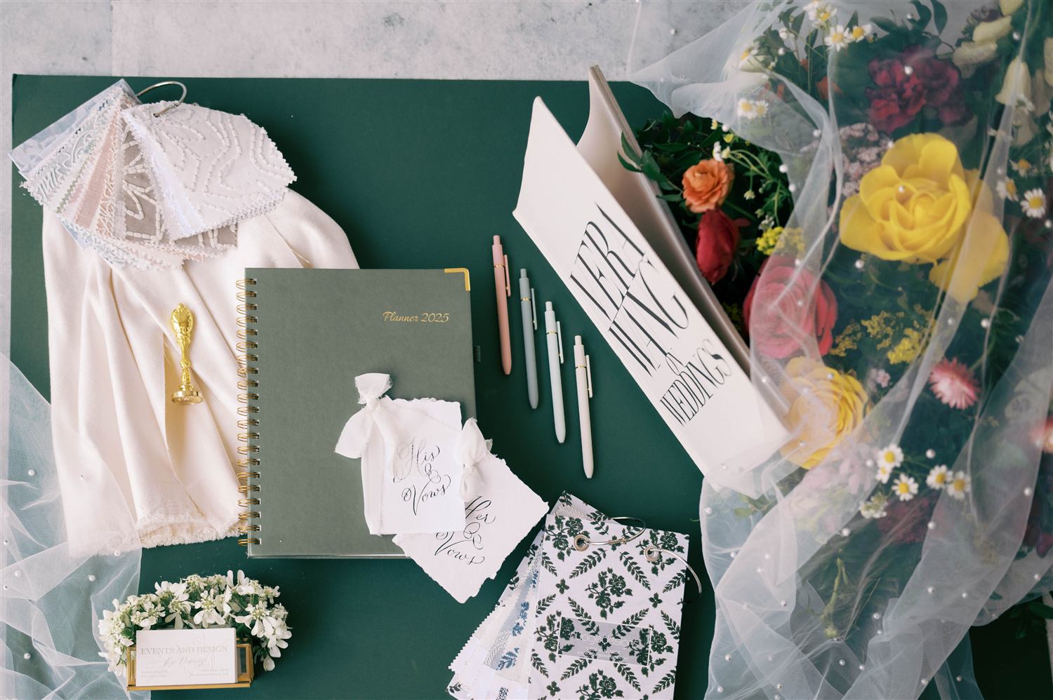 A flat lay of planning notebooks, fabric swatches, and a bouquet corner